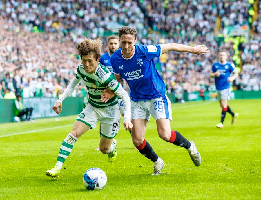 Two players tussle for the ball in a Rangers vs Celtic match.