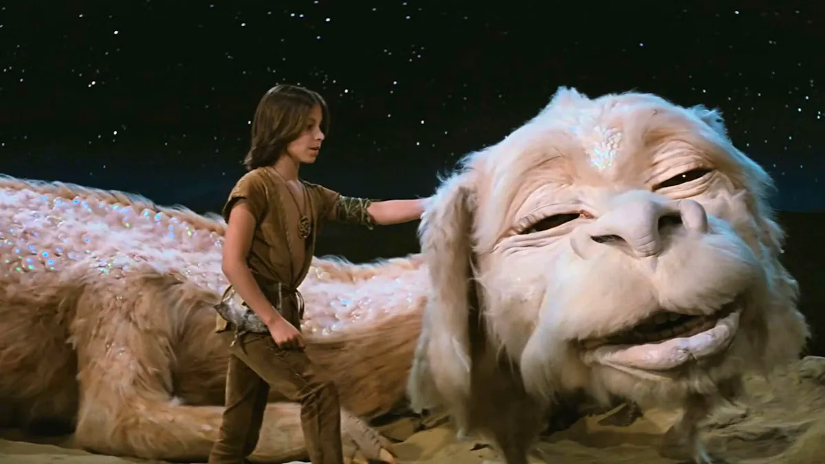 Atreyu, a young adventurer, pets Falkor, a huge, white, furry, doglike dragon