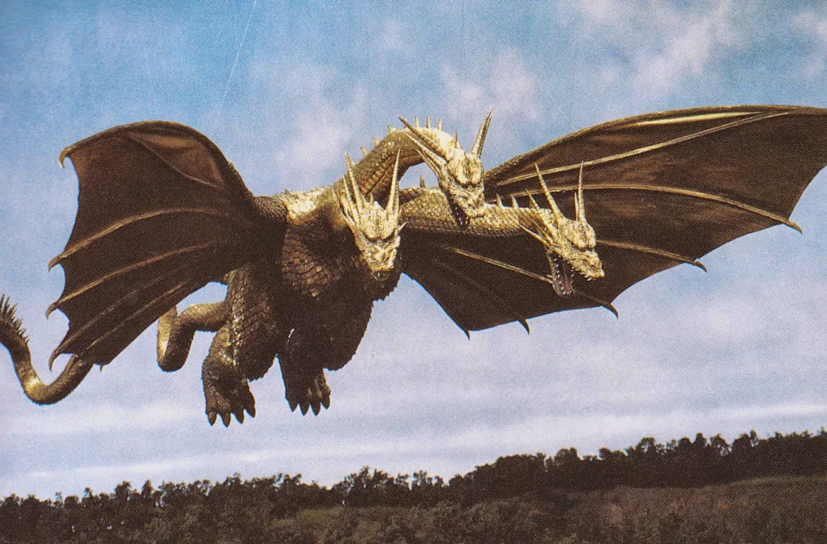King Ghidorah, a huge, three-headed golden dragon, flies over a forest