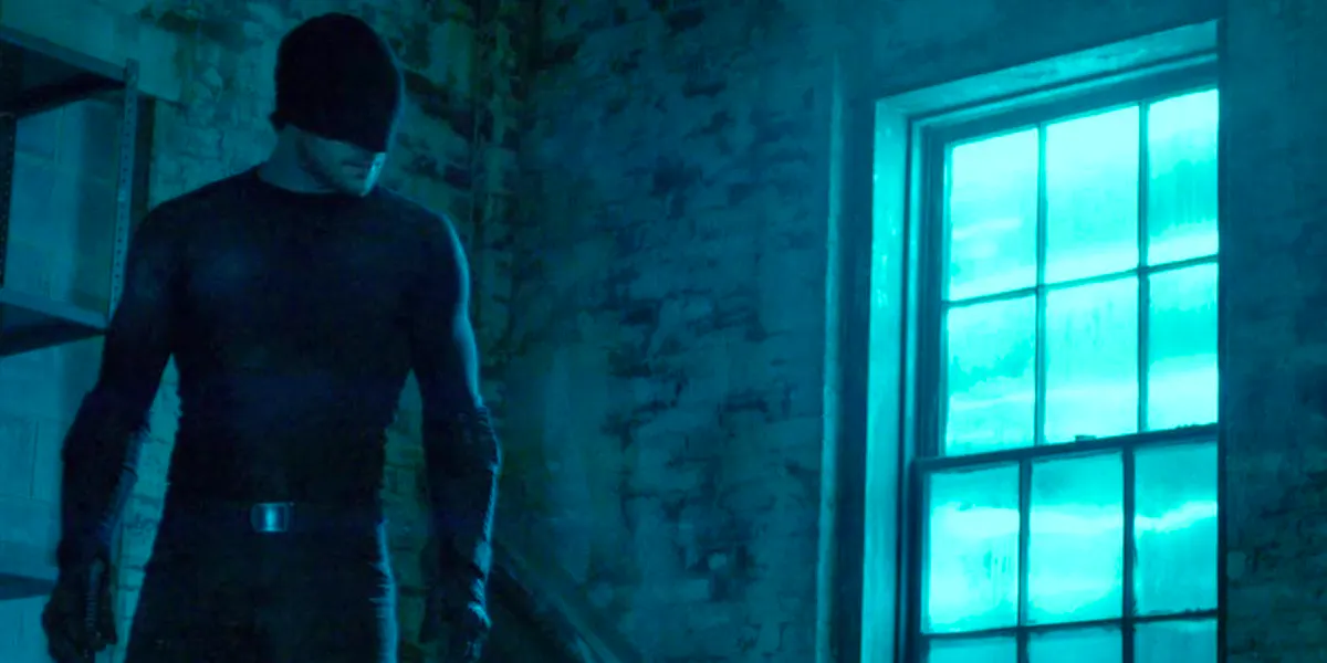 Daredevil, in his simple black suit, stands in an abandoned warehouse