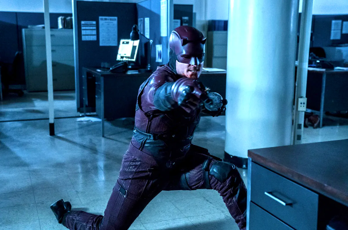 Ben Poindexter, dressed in the Daredevil costume, throws desk objects as weapons in an office building