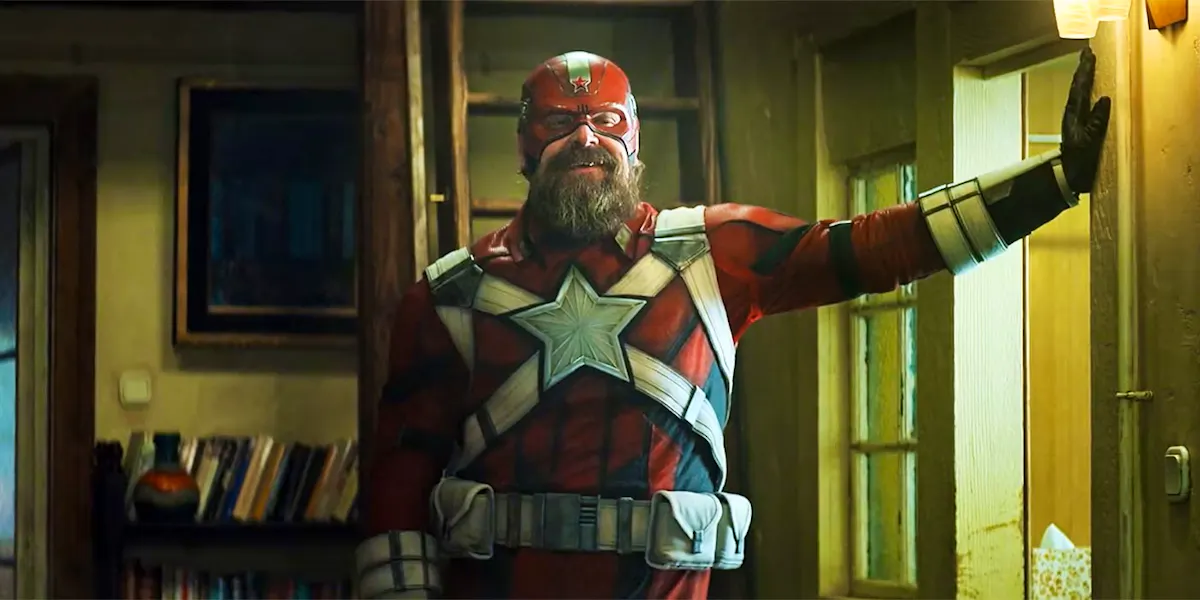 Red Guardian, a Russian superhero played by David Harbour, stands awkwardly leaning against a wall