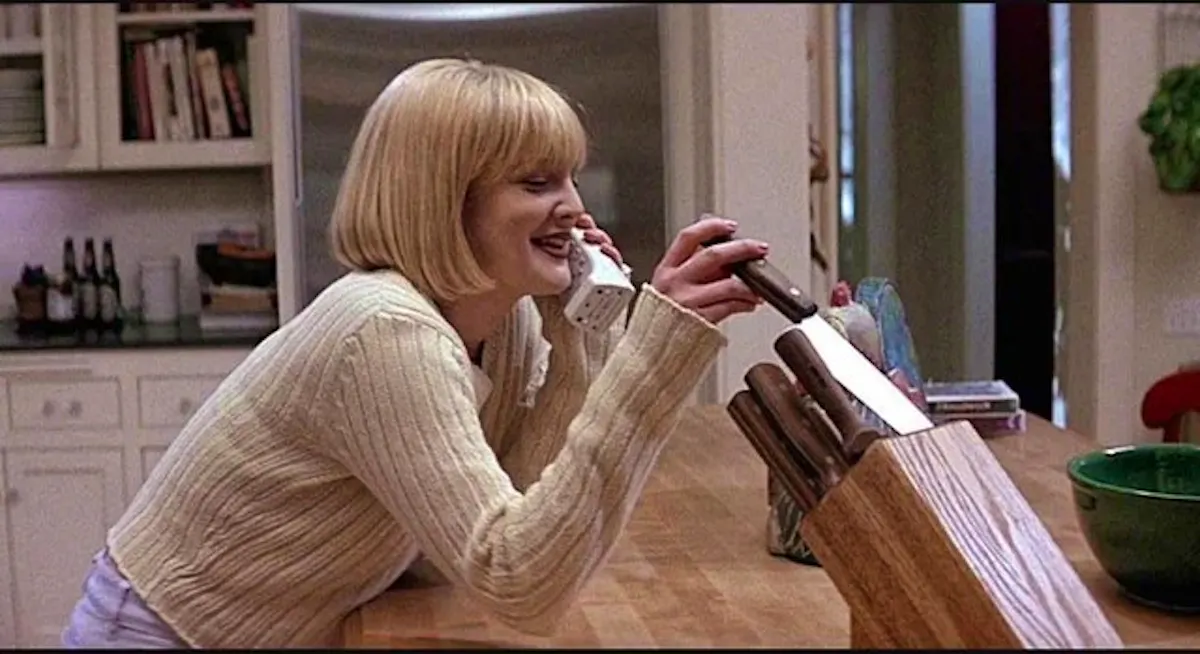 Casey, played by Drew Barrymore, on the phone in her kitchen, absently playing with knives in a block