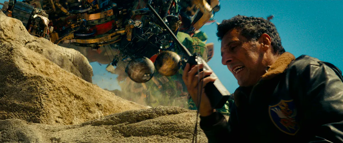 A man yells into a walkie talkie underneath a paid of giant wrecking balls